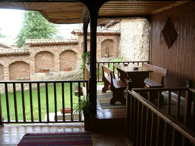 a porch of a house with a table on a balcony at Sarafova Guest House in Koprivshtitsa