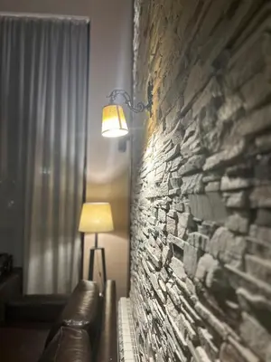 a room with a stone wall with a couch and a lamp at The Nature View Suite, part of Terra Complex & Spa in Bansko
