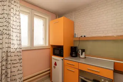a small kitchen with orange cabinets and a refrigerator at Charming Artistic Central Apartment in Sofia