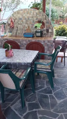 a table and chairs on a patio with a stone oven at Къща за гости в селска местност in Petrich