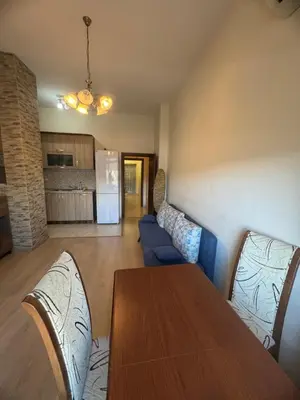 a living room with a table and a blue couch at Лукс апартамент Базилика отделен вход in Sandanski