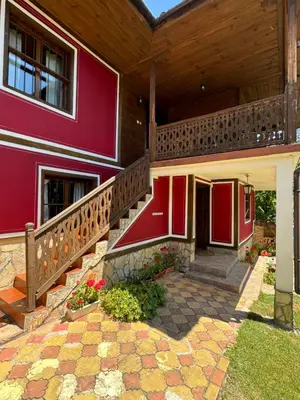a red house with a staircase and a porch at Borimechkova Kashta in Koprivshtitsa