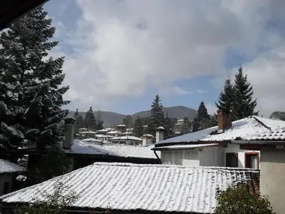 a snow covered roofs of houses with trees and mountains at Borimechkova Kashta in Koprivshtitsa