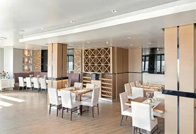 a restaurant with white chairs and tables and wine racks at Face Hotel in Sofia