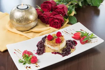a white plate with a dessert and strawberries on a table at Face Hotel in Sofia