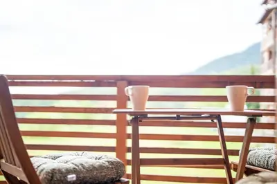 a table on a balcony with two cups on it at Best Mountain View Chalet in Bansko