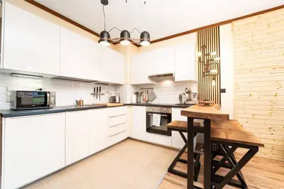 a kitchen with white cabinets and a wooden table at Best Mountain View Chalet in Bansko