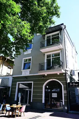 a green building with tables and chairs in front of it at The House - Central Boutique Apartments in Kyustendil