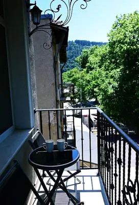 a table on a balcony with two cups on it at The House - Central Boutique Apartments in Kyustendil