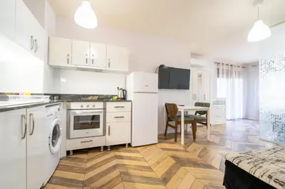 a kitchen with white cabinets and a wooden floor at Azurro Residence in Sofia