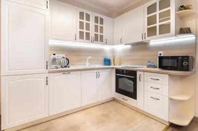 a white kitchen with white cabinets and a microwave at Heart of the City 2-Bedroom Apartment in Plovdiv