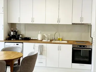 a kitchen with white cabinets and a table with chairs at Katerina Apartments in Velingrad