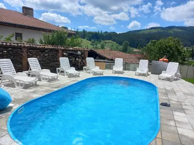a large swimming pool with chairs and a patio at Kъща за гости Демария in Koprivshtitsa