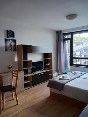 a bedroom with a bed and a desk and a television at Аспен валей С420 in Razlog