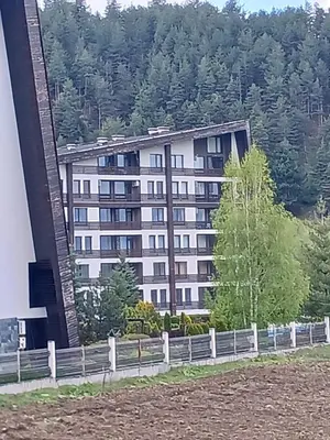 a large white building with trees in the background at Аспен валей С420 in Razlog