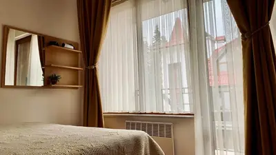 a bedroom with a bed and a large window at Апартамент Касъл in Pamporovo