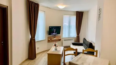 a living room with a couch and a tv at Апартамент Касъл in Pamporovo