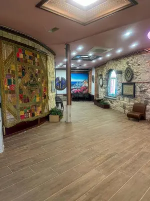 a large room with a stone wall with a large rug at ТРАКАРТ-ПАРК in Plovdiv