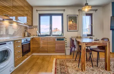 a kitchen with a wooden table and a dining room at Pastels - 2BD in Trinity Bansko with underground parking by Flat Mаnager in Bansko