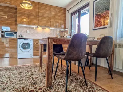 a kitchen with a wooden table and two chairs at Pastels - 2BD in Trinity Bansko with underground parking by Flat Mаnager in Bansko
