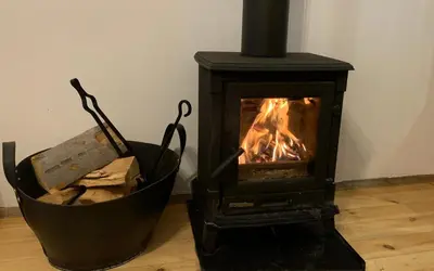 a black stove with a fire in a room at Къща за гости Константин и Елена - гр. Девин in Devin