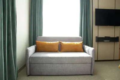 a couch with an orange pillow in a room at Hotel Forum City in Pazardzhik