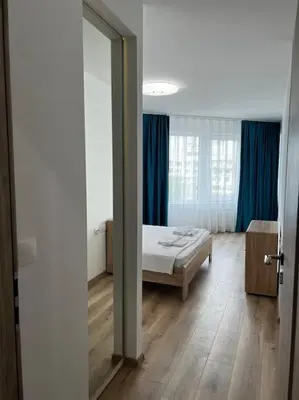 a bedroom with a bed and a window with blue curtains at Blue & Gold Stylish Apartment in Sofia
