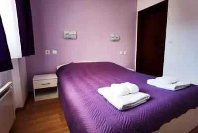 a purple bed with two towels on top of it at Апартамент 204 Студенец in Pamporovo