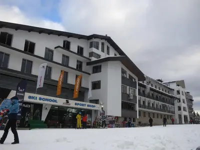 a person walking in the snow in front of a building at Апартамент 204 Студенец in Pamporovo