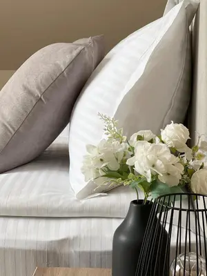 a white couch with pillows and a vase of flowers at Hotel BLISS Sofia Airport Self Check In in Kazichene