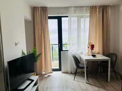 a living room with a table and a television at Classic Modern Apartment with Parking Place in Sofia