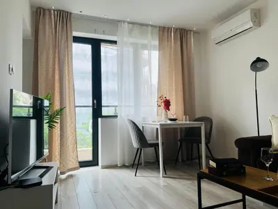 a living room with a dining room table and a room with a window at Classic Modern Apartment with Parking Place in Sofia