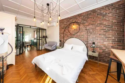 a bedroom with a white bed and a brick wall at Heart of the Center, 2Bedroom View Lux Apartment in Sofia