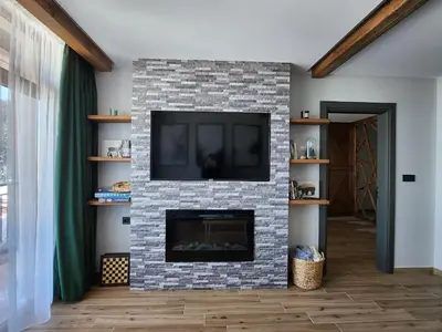 a living room with a brick fireplace with a tv at Pine & Wine Bathtub Apartment in Pamporovo