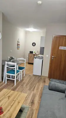a living room with a table and a kitchen at Minkov Apartments, Пампорово - Замъка 2 in Pamporovo