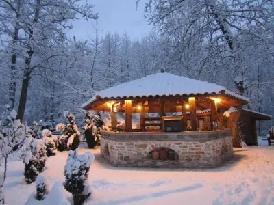 a gazebo in the snow with people standing around it at Парк - Хотел Макензен in Melnik