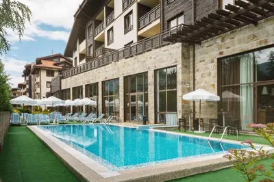 a swimming pool with chairs and umbrellas next to a building at Terra complex -D6 - Balkan private apartment-Spa Sking Golf and Relax in Razlog