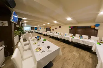 a banquet hall with white tables and white chairs at Forest Nook Villas in Pamporovo