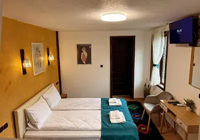 a hotel room with a bed and a desk and a table at Rooms in Leshten in Leshten