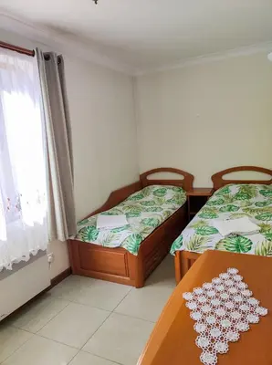 two beds in a room with a table and a window at Терасите - Къща 1 in Ribarica