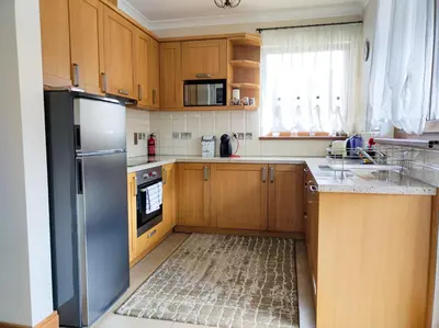 a kitchen with wooden cabinets and a stainless steel refrigerator at Терасите - Къща 2 in Ribarica