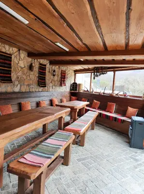 a room with wooden tables and benches in a building at Терасите - Къща 2 in Ribarica