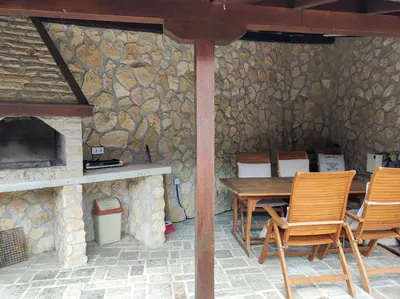 a patio with a table and chairs and a stone wall at Терасите - Къща 3 in Ribarica