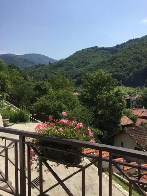 a balcony with a bench and flowers on a mountain at Терасите - Къща 4 in Ribarica