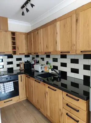 a kitchen with wooden cabinets and black and white tiles at Терасите - Къща 4 in Ribarica