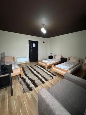 a living room with three beds and a rug at СТАРАТА КЪЩА in Sovolyano