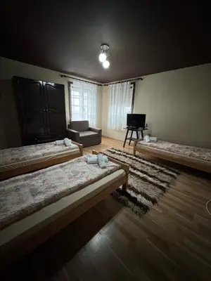 a room with three beds and a television in it at СТАРАТА КЪЩА in Sovolyano
