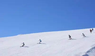 a group of people skiing down a snow covered slope at Anna Apartment near Gondola in Bansko