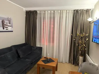 a living room with a black couch and a table at Anna Apartment near Gondola in Bansko