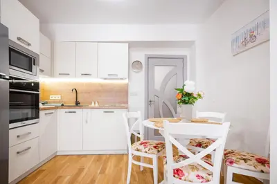 a kitchen with white cabinets and a table with chairs at 1BD Elegance on Vasil Levski Boulevard by Flat Mаnager in Sofia